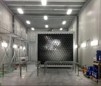 Interior of a stainless steel spray pickling and passivation bay featuring stainless steel fabrication equipment and organized workspaces, showcasing a hexagonal metal structure and bright overhead lighting for custom precision metal fabrication projects.