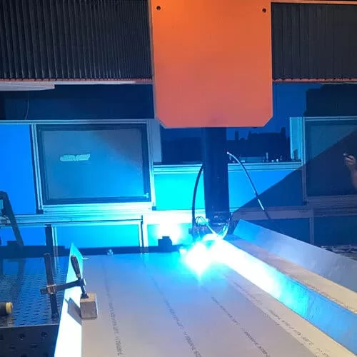 Precision laser welding machine butt welding stainless steel with a blue laser beam in a clean industrial workspace.